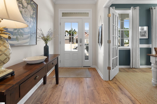 foyer with light wood-style flooring, baseboards, and ornamental molding