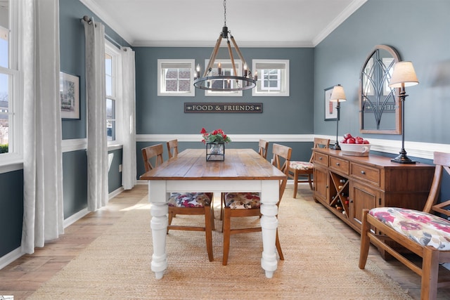 dining area with baseboards, a notable chandelier, ornamental molding, and light wood finished floors