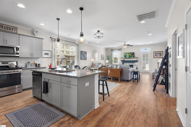 kitchen featuring visible vents, gray cabinets, a sink, stainless steel appliances, and crown molding