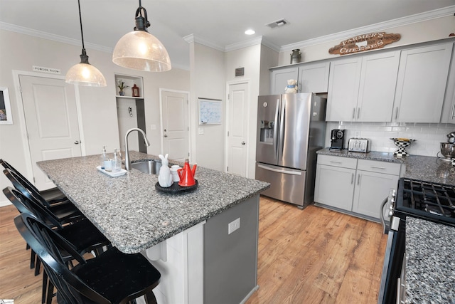 kitchen featuring stone counters, appliances with stainless steel finishes, crown molding, and light wood finished floors