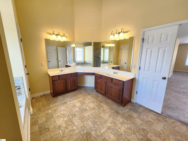 full bathroom with stone finish floor, a high ceiling, baseboards, and a sink