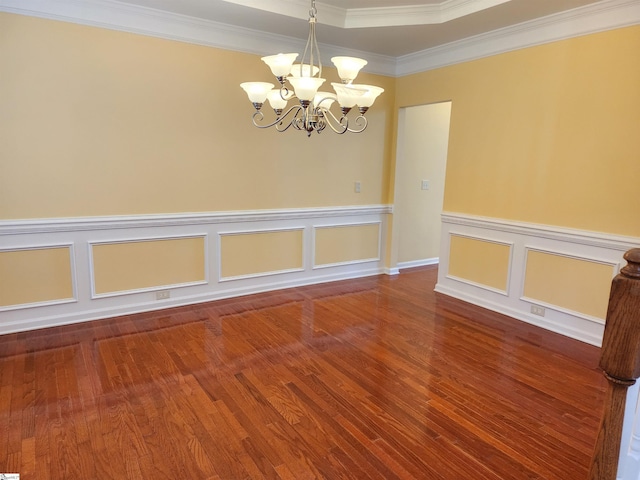 spare room with wood finished floors, crown molding, a notable chandelier, and wainscoting