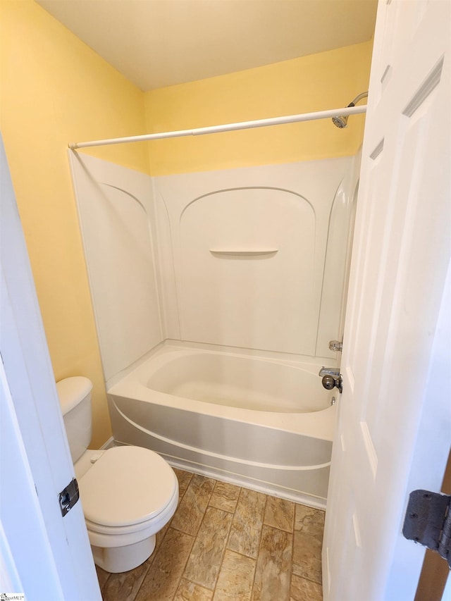 bathroom featuring stone finish flooring, toilet, and shower / tub combination