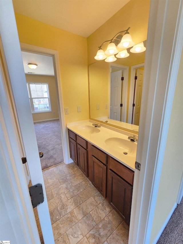 bathroom with baseboards, a sink, and double vanity