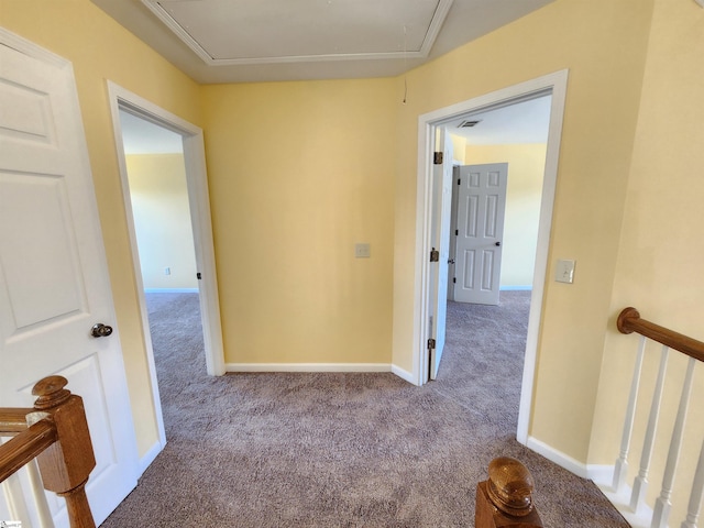 corridor with attic access, carpet, and baseboards