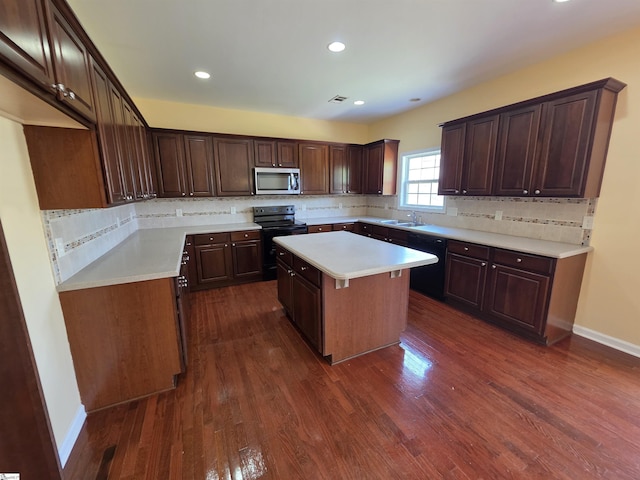 kitchen featuring light countertops, a kitchen island, backsplash, and black appliances