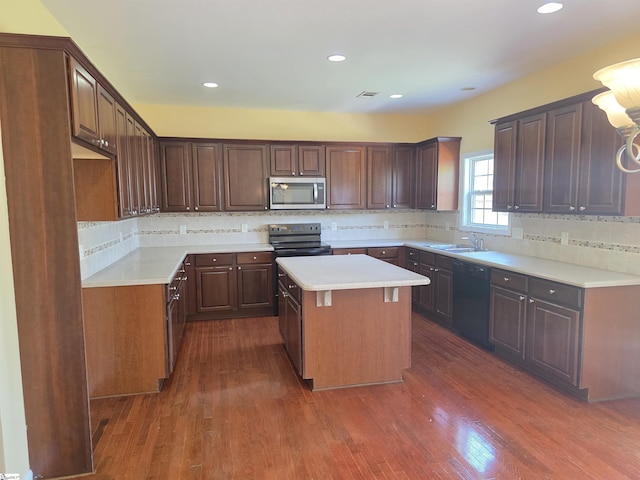 kitchen with a sink, a center island, decorative backsplash, and black appliances