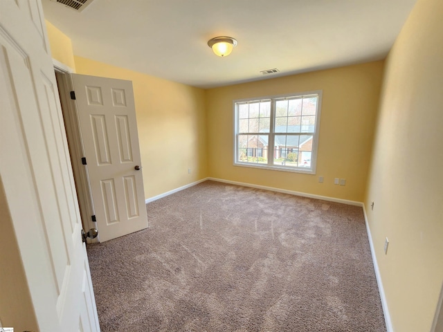 spare room with carpet floors, visible vents, and baseboards