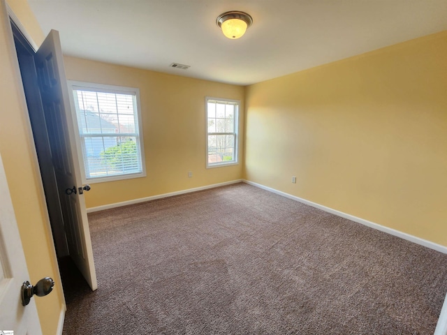 carpeted empty room featuring baseboards and visible vents