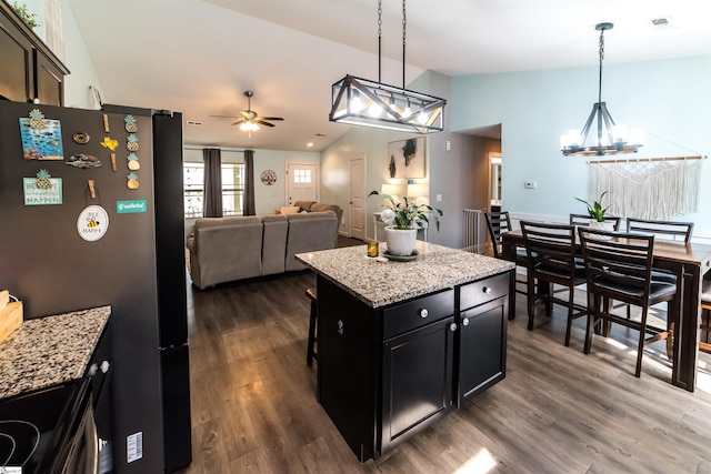 kitchen featuring dark cabinetry, lofted ceiling, freestanding refrigerator, dark wood-type flooring, and ceiling fan with notable chandelier