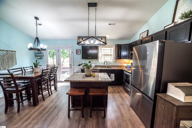 kitchen with stainless steel appliances, a kitchen island, a notable chandelier, and visible vents