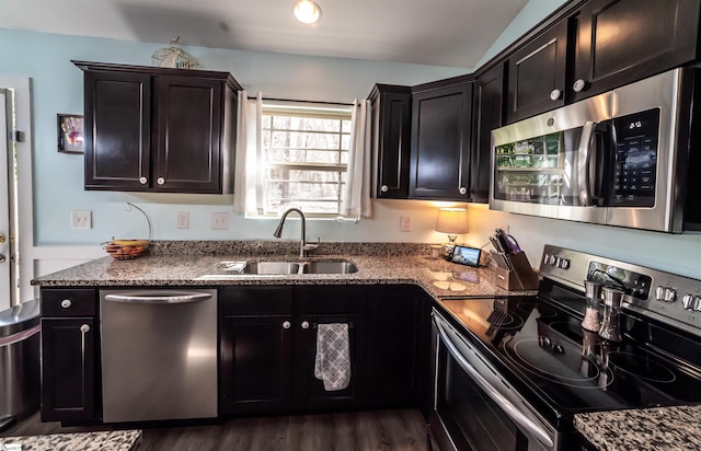 kitchen with dark stone countertops, appliances with stainless steel finishes, dark wood-type flooring, and a sink