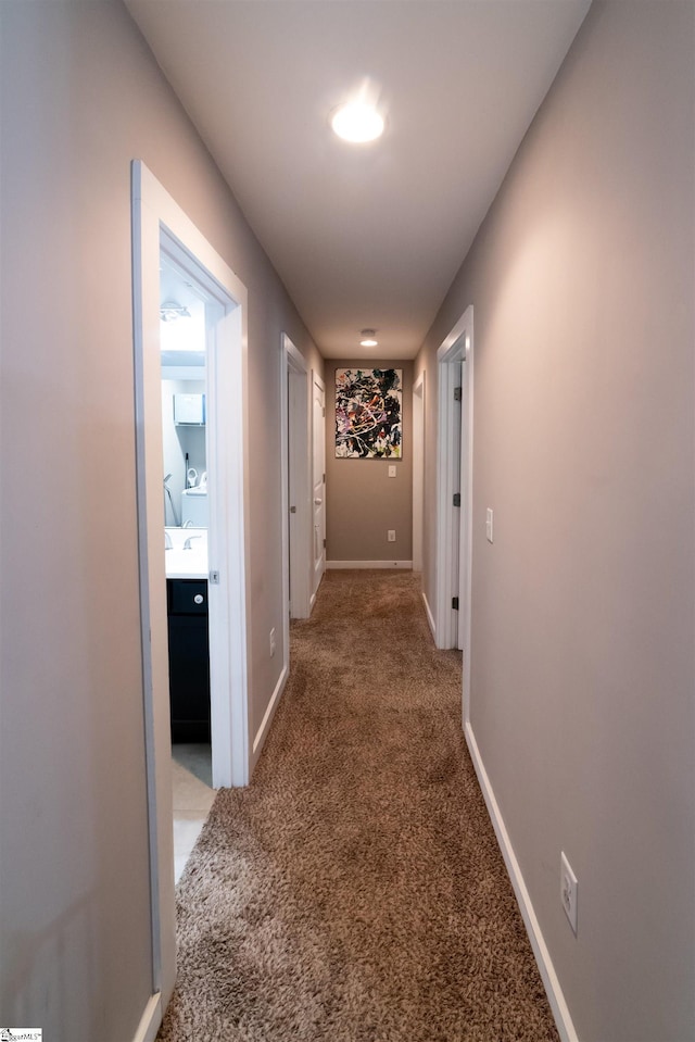 hallway featuring carpet and baseboards