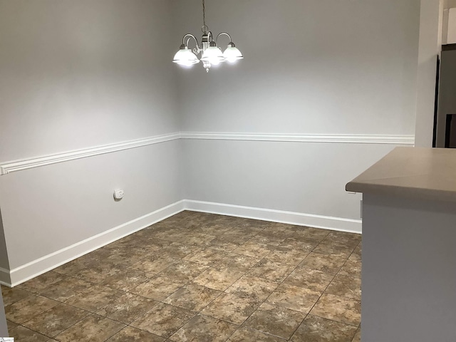 unfurnished dining area with baseboards and an inviting chandelier