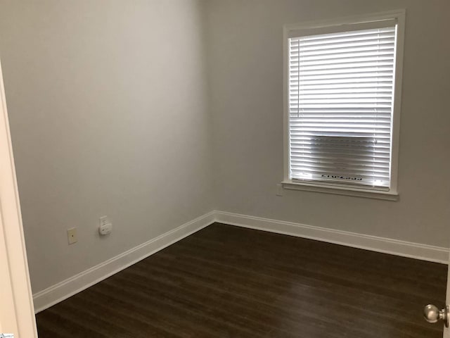 spare room featuring dark wood-type flooring and baseboards