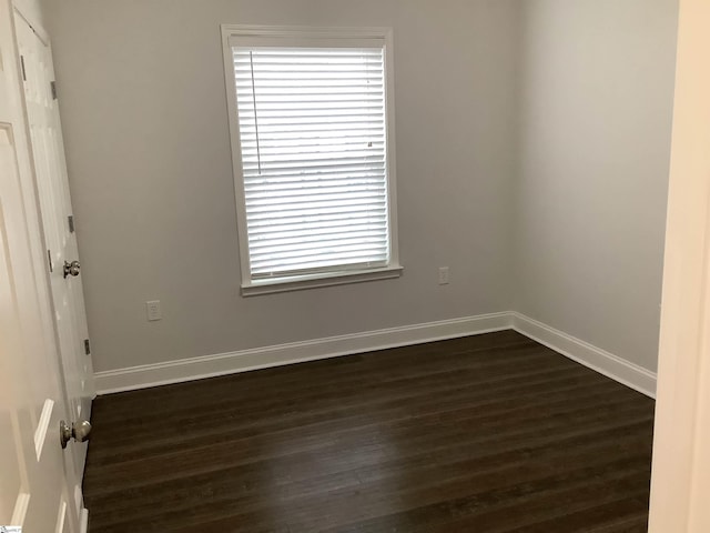 unfurnished room with dark wood finished floors and baseboards