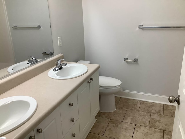 full bath featuring double vanity, baseboards, and a sink