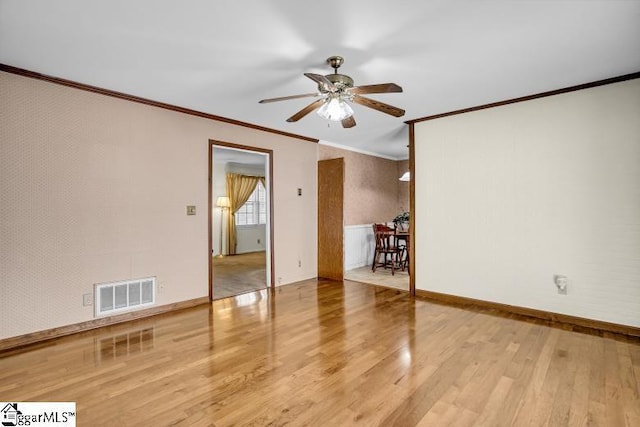 spare room featuring visible vents, wood finished floors, ceiling fan, and crown molding