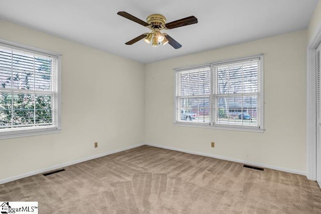 spare room featuring ceiling fan, baseboards, visible vents, and light carpet