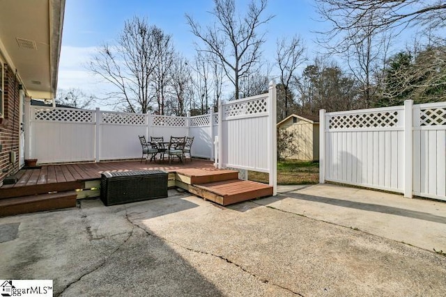 view of patio with a wooden deck, outdoor dining area, and fence