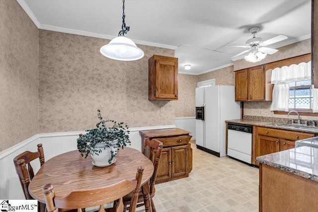 kitchen featuring wallpapered walls, white appliances, a wainscoted wall, and a sink