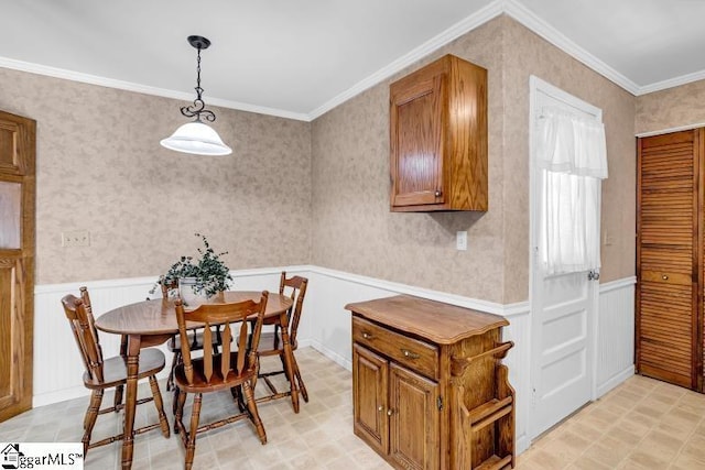 dining room with wallpapered walls, a wainscoted wall, and ornamental molding