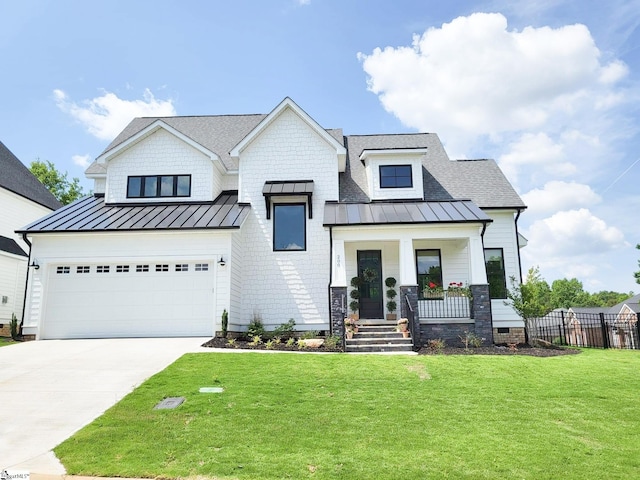 modern farmhouse style home with driveway, a standing seam roof, covered porch, a front yard, and metal roof