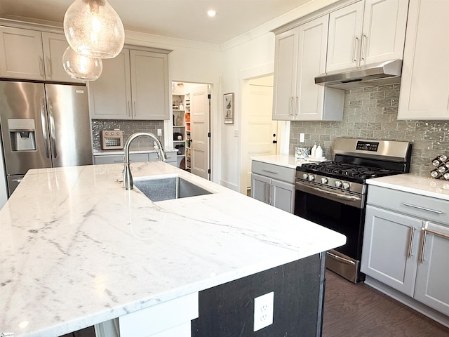 kitchen with light stone countertops, under cabinet range hood, ornamental molding, appliances with stainless steel finishes, and a sink