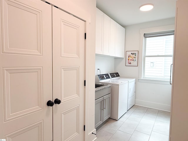 laundry area with light tile patterned flooring, cabinet space, baseboards, and separate washer and dryer