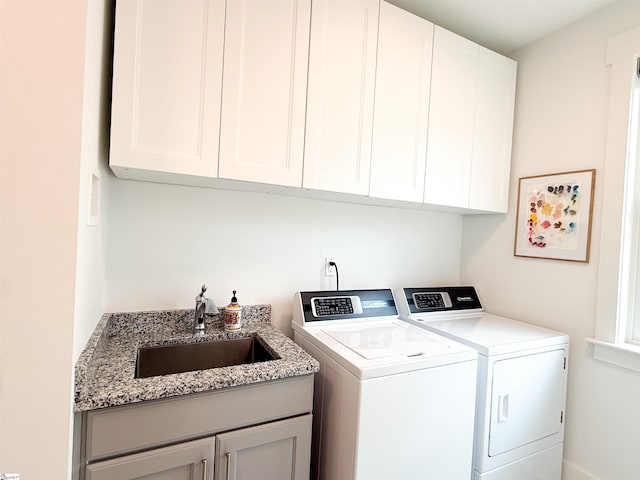 washroom featuring washing machine and dryer, cabinet space, and a sink