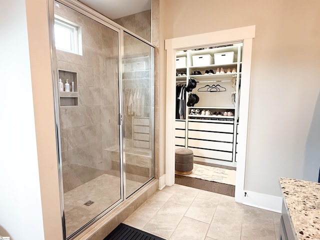 bathroom featuring tile patterned flooring, a shower stall, and a spacious closet