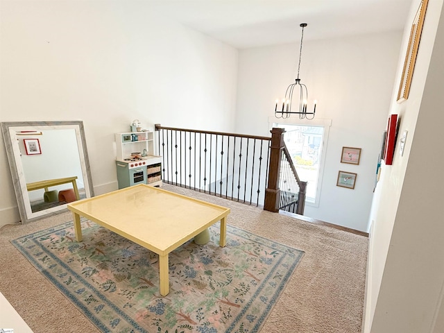 living area with an upstairs landing, baseboards, carpet floors, and a chandelier