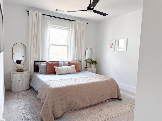 bedroom featuring visible vents, light colored carpet, baseboards, and ceiling fan