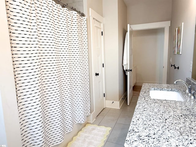 full bath featuring a sink, curtained shower, baseboards, and tile patterned flooring