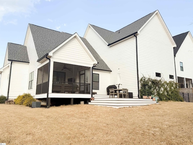 back of property featuring roof with shingles, a yard, and a sunroom