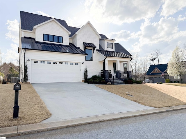 modern farmhouse style home featuring cooling unit, metal roof, a garage, driveway, and a standing seam roof