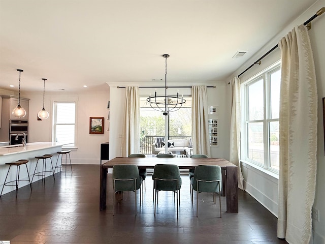 dining space with a healthy amount of sunlight, dark wood-style flooring, and a chandelier