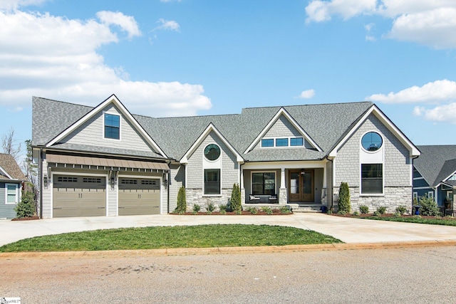 view of front of property featuring a garage, stone siding, driveway, and roof with shingles