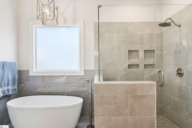 full bathroom featuring a soaking tub, wainscoting, a stall shower, and tile walls