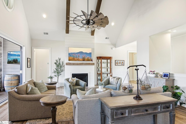 living room with light wood-type flooring, visible vents, high vaulted ceiling, a large fireplace, and ceiling fan