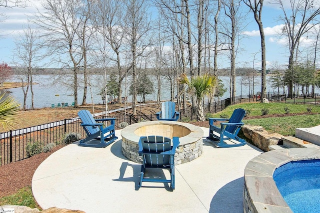 view of patio with a fire pit, a fenced backyard, and a water view