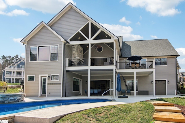 back of house featuring a patio area, an outdoor pool, and a balcony