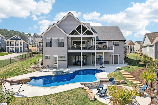 back of house featuring a pool with connected hot tub, a residential view, a balcony, a fenced backyard, and a patio area