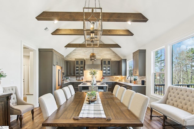 dining room with visible vents, lofted ceiling with beams, and wood finished floors