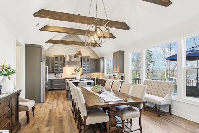 dining space with visible vents, light wood finished floors, high vaulted ceiling, beam ceiling, and a notable chandelier