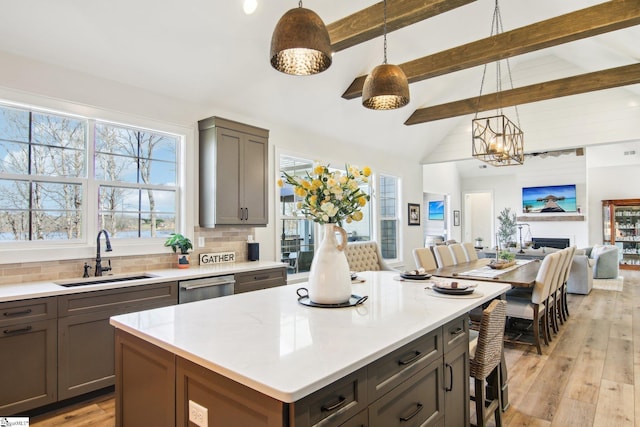 kitchen featuring backsplash, dishwasher, gray cabinetry, and a sink