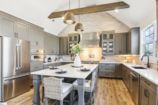 kitchen with backsplash, appliances with stainless steel finishes, wall chimney range hood, and a sink