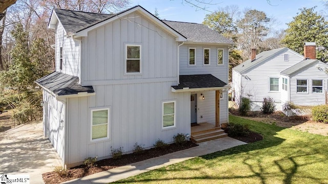 modern farmhouse style home featuring board and batten siding, a shingled roof, and a front yard