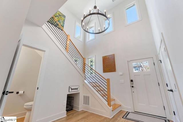 entryway featuring stairway, a notable chandelier, plenty of natural light, and light wood finished floors