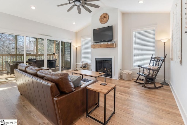 living room featuring a ceiling fan, baseboards, light wood-style floors, and a fireplace